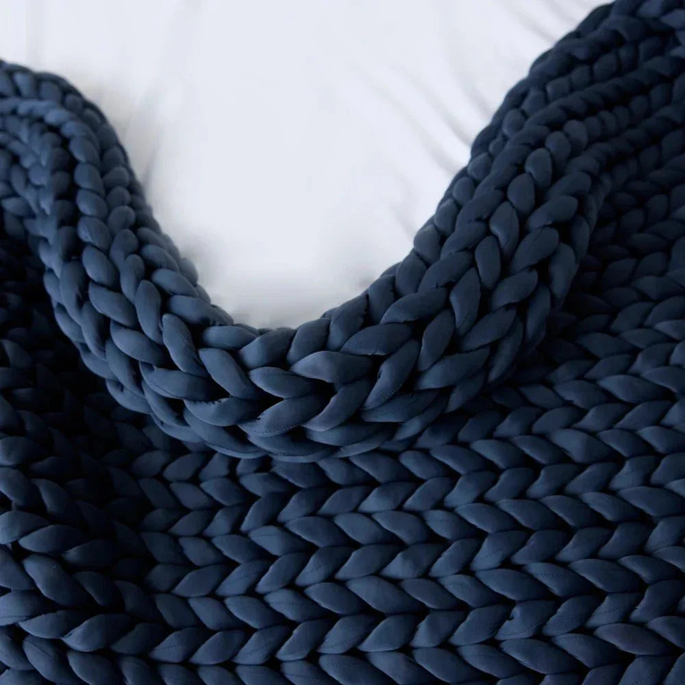 Chunky knit cooling weighted blanket in pacific blue on a white bed