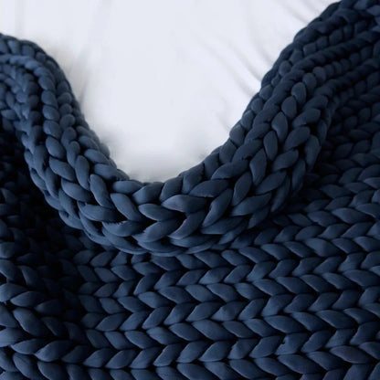 Chunky knit cooling weighted blanket in pacific blue on a white bed