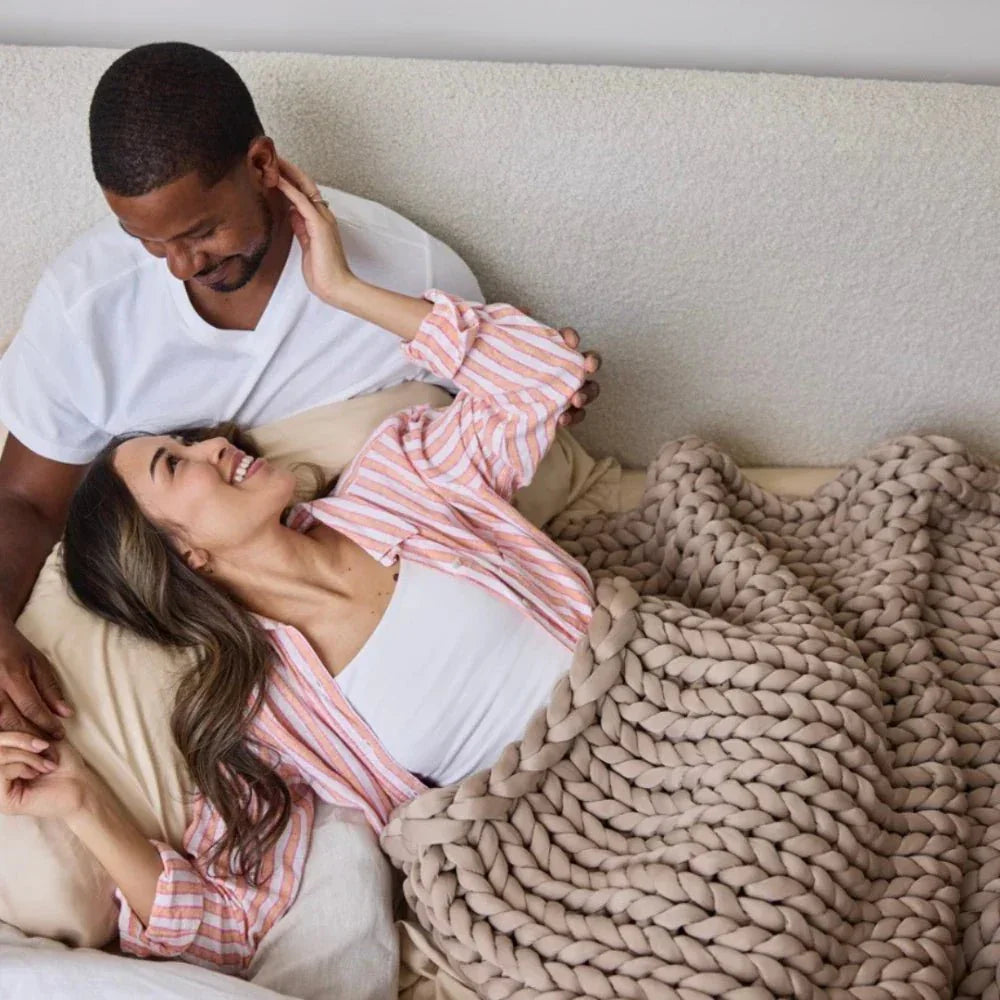 Couple relaxing in bed under a chunky knit cooling weighted blanket in coastal sand color