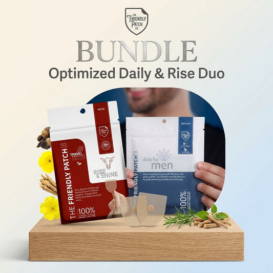 A product bundle main image featuring The Friendly Patch Co. wellness patches arranged on a light-colored wooden pedestal against a clean, gradient background. On the left sits the red and white "Rise & Shine" patch pack, accented by illustrations of a bull, yellow flowers, and botanical roots. On the right, a person's hands hold the blue and white "Daily for Men" patch pack. In front of the packaging, loose, transparent square patches are displayed alongside fresh green rosemary sprigs and herbal roots. 