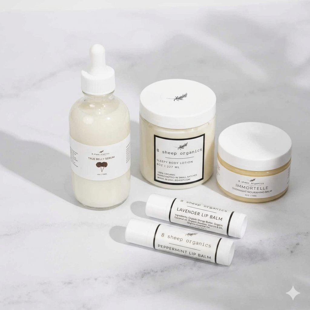 Four skincare products from 8 Sheep Organics arranged on a light marble surface: a dropper bottle of tea tree body wash, a candle, a body butter jar, and two lip balms.