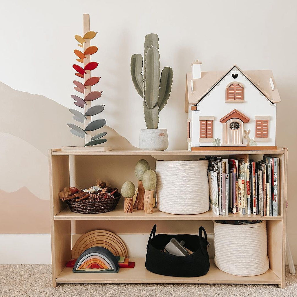 Wooden shelf with toys, books, and decorative items against a plain wall.