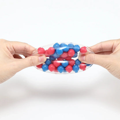 Hands squeezing a clear sensory stress ball with blue and pink beads inside, for fidgeting