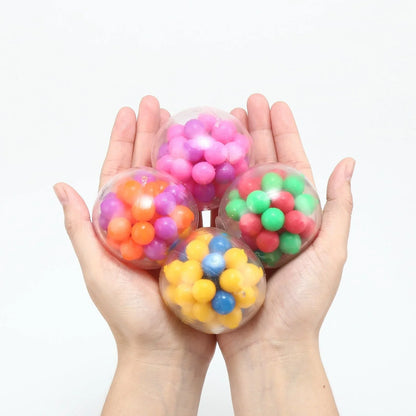 Hands holding four colorful sensory stress balls with bright beads for fidget or therapy use