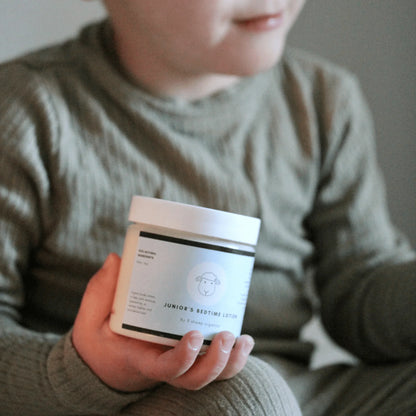 Child in green pajamas holding Junior's Bedtime Lotion jar for sleep support