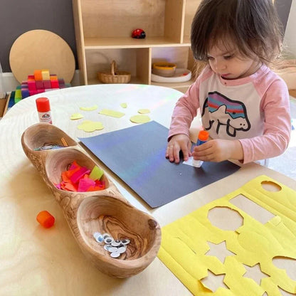 Young child doing sensory-friendly art and crafts at a table with colorful shapes and glue