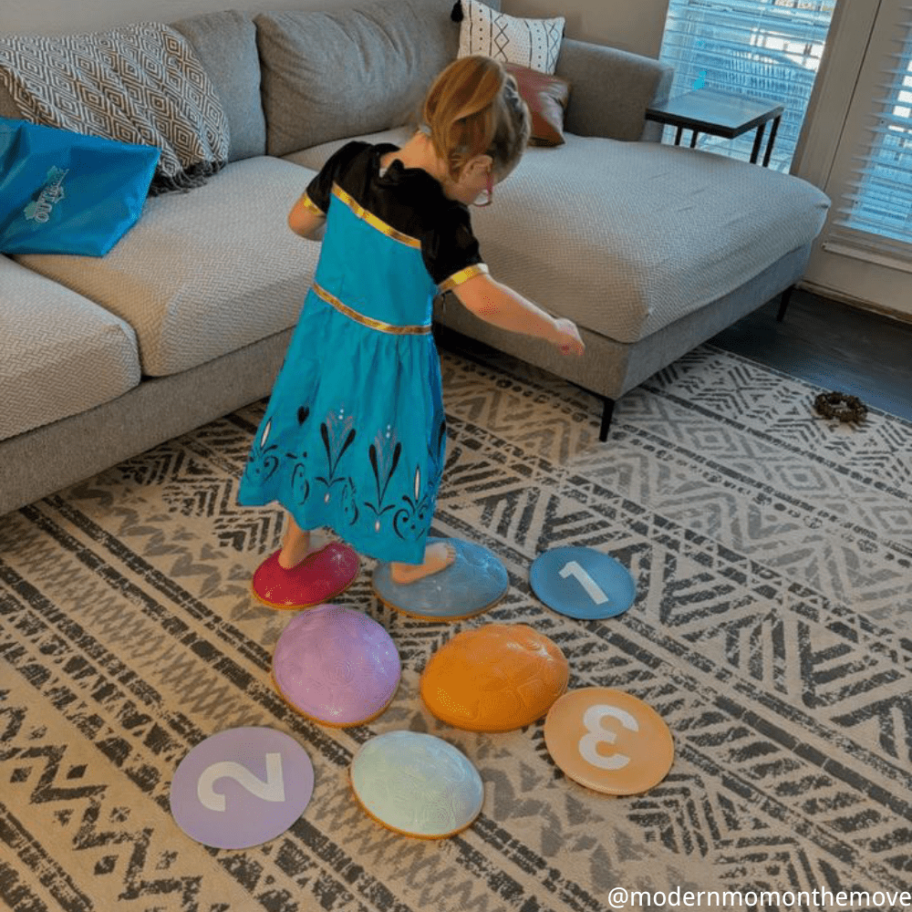 Child playing with colorful number pads on a patterned rug in a living room.