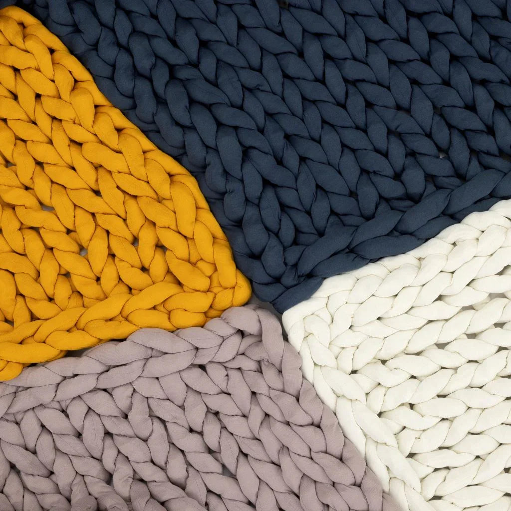 Chunky knit blankets in marigold, navy, cream, and mauve, ideal for sensory comfort.