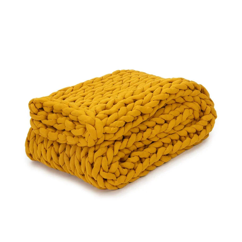 Folded marigold yellow chunky knit weighted blanket on white background