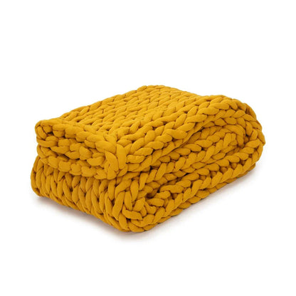 Folded marigold yellow chunky knit weighted blanket on white background