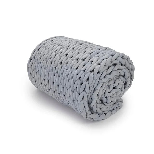 Rolled light grey chunky knit weighted blanket on white background