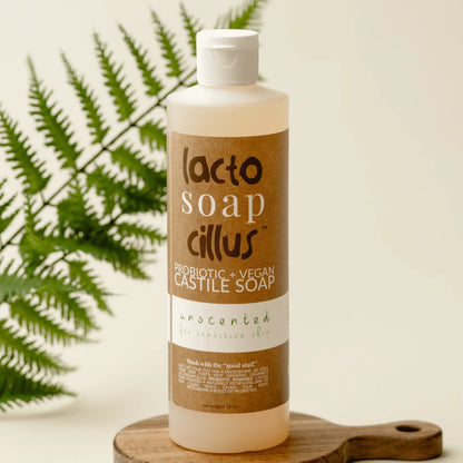 Unscented probiotic vegan Castile soap bottle for sensitive skin on wooden tray with fern