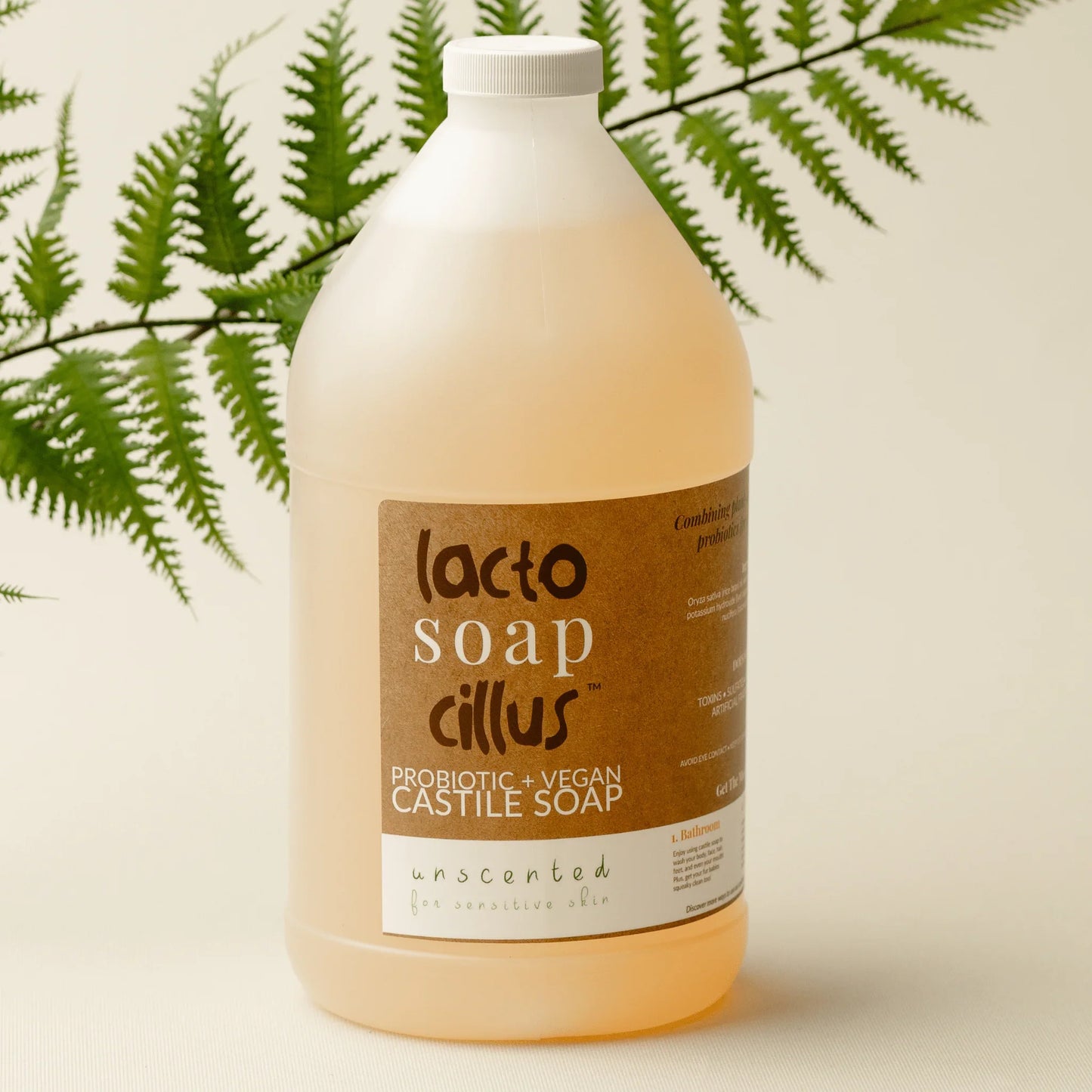 64 oz unscented probiotic vegan Castile soap bottle for sensitive skin with plant in background