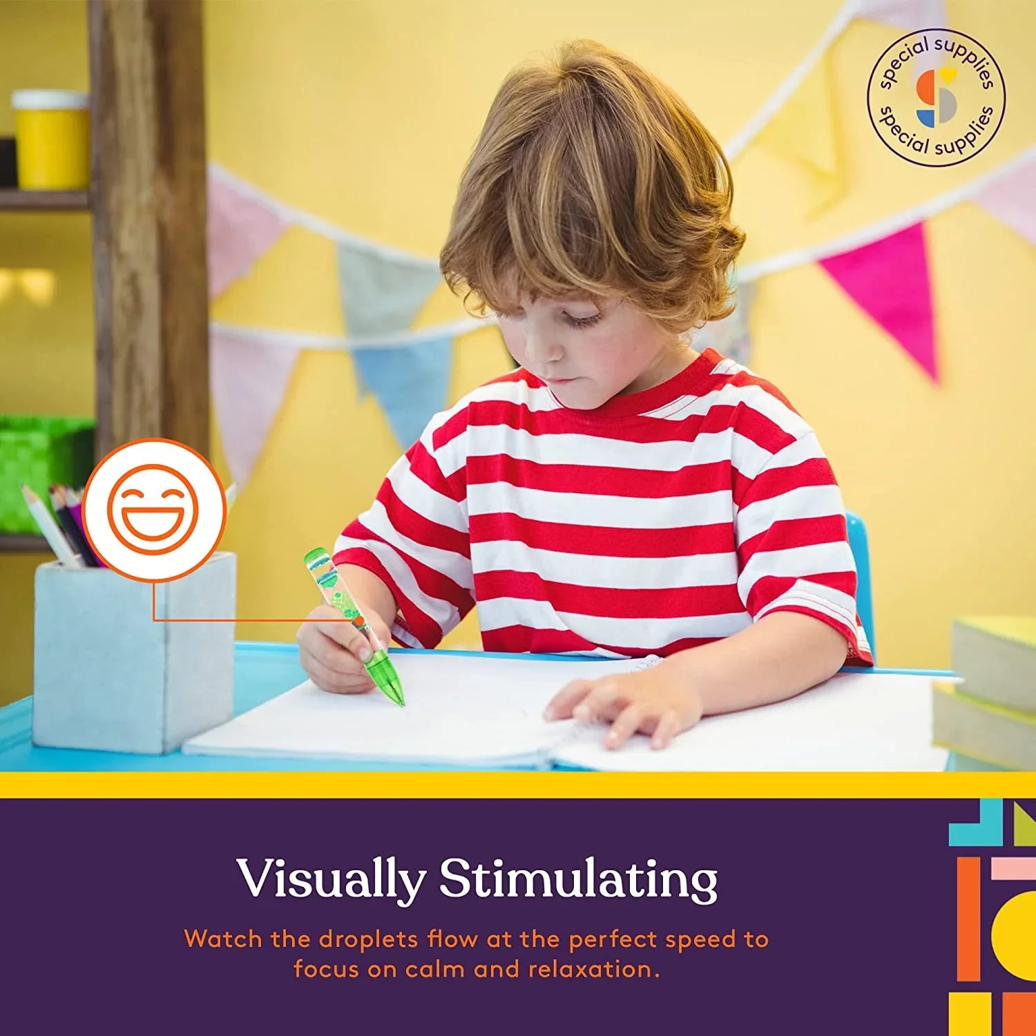 Child in red striped shirt using sensory tool to focus while drawing at a desk, calm classroom setting.