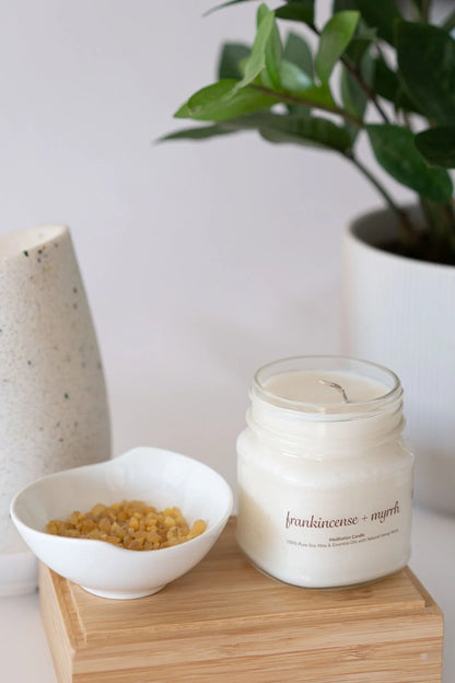 Frankincense and myrrh soy wax meditation candle with essential oils, beside resin bowl, on wood