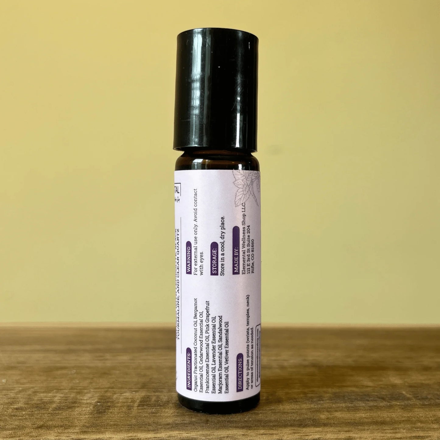 Natural anxiety relief essential oil roller with lavender label on wood surface