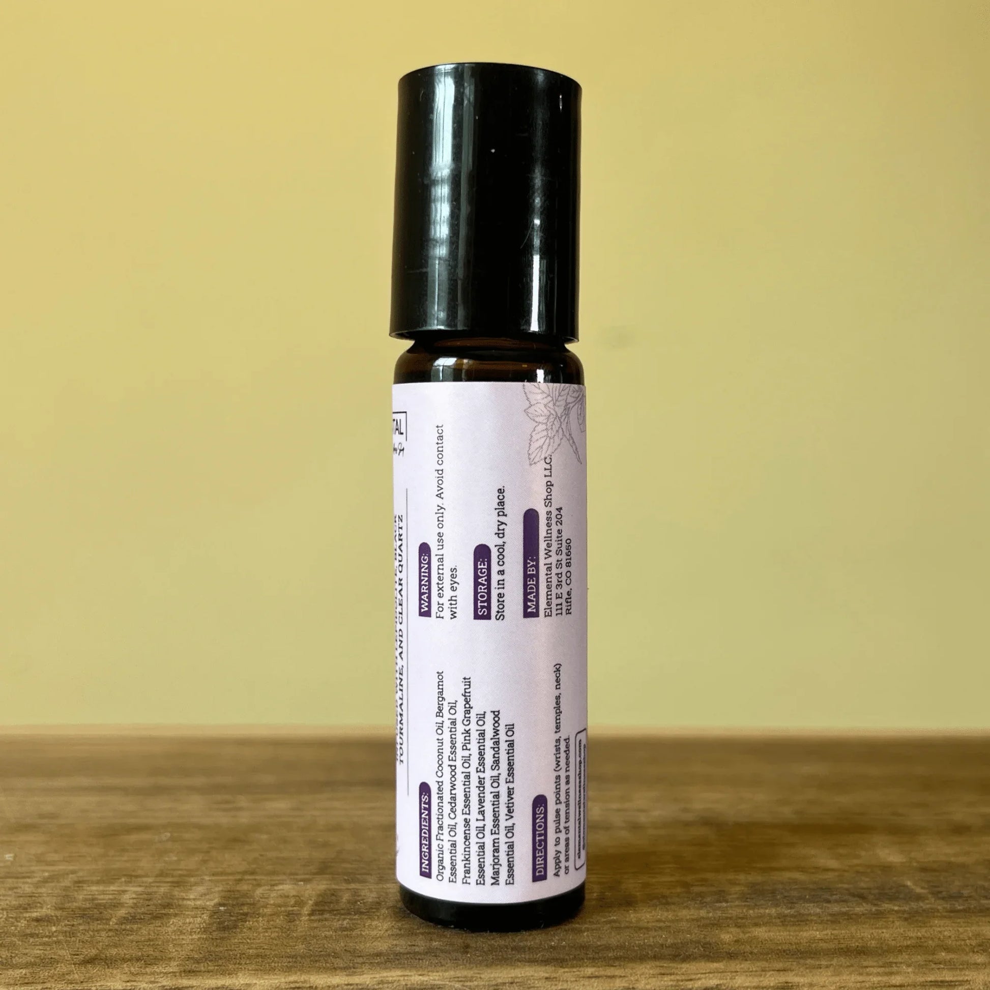 Natural anxiety relief essential oil roller with lavender label on wood surface