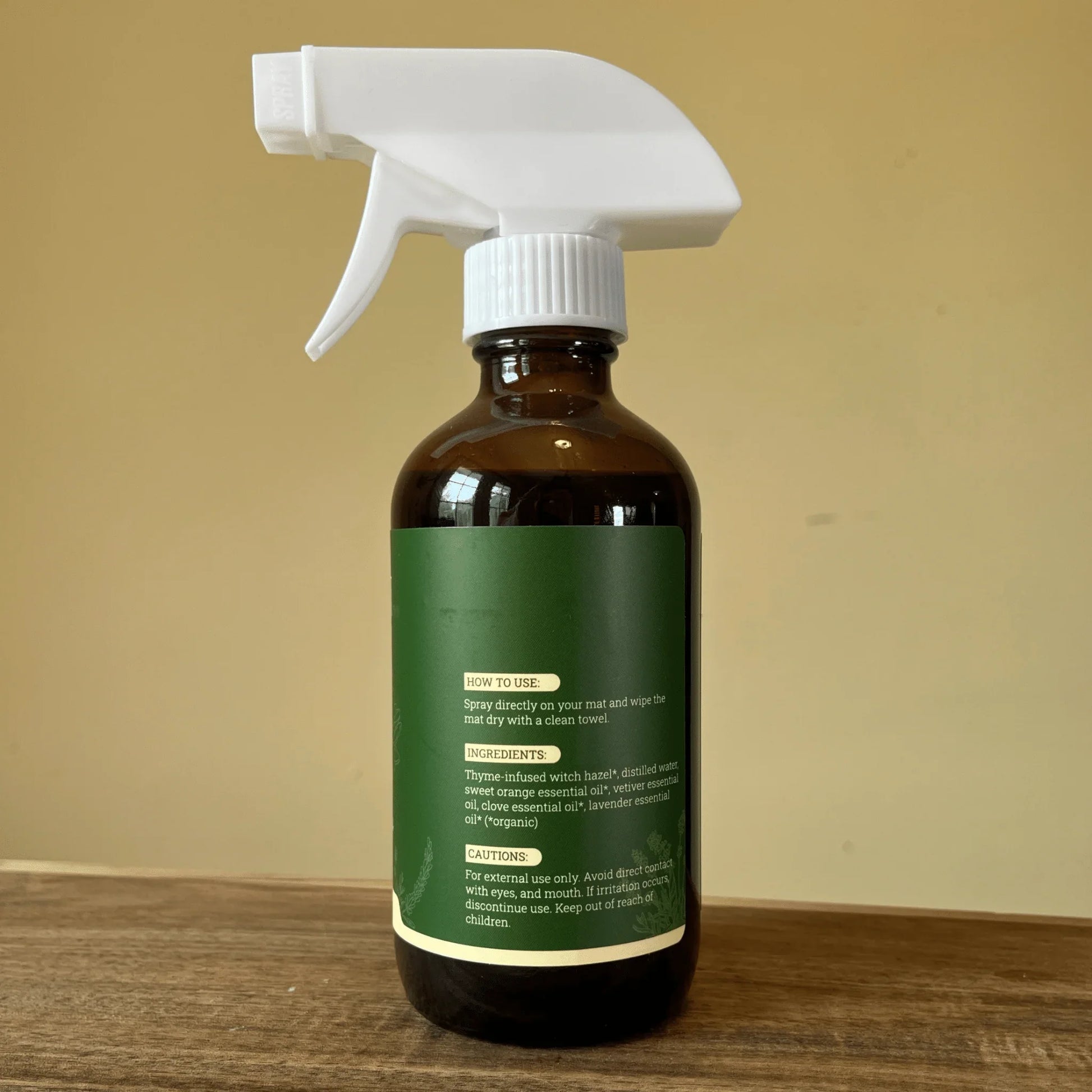 Natural yoga mat cleaner spray bottle with green label on wooden surface