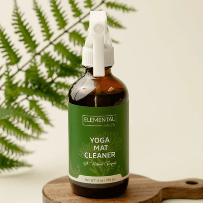 Natural yoga mat cleaner spray in amber bottle with green label, fern leaf background