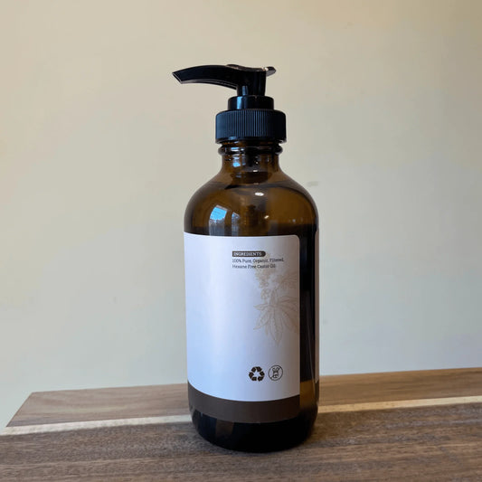 Amber glass pump bottle of organic hexane-free castor oil on a wooden surface