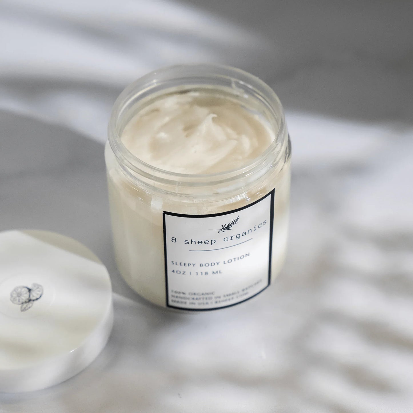 8 Sheep Organics Sleepy Body Lotion jar with creamy texture on marble surface