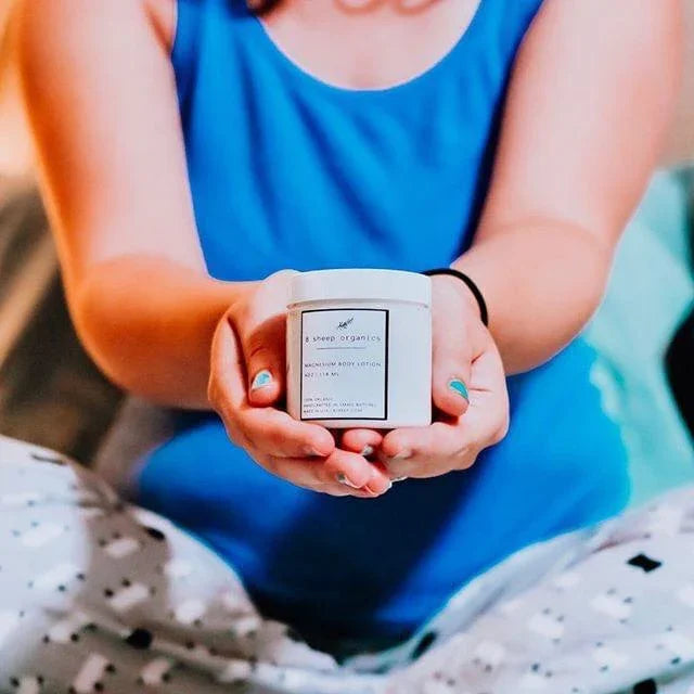 Person in blue shirt holding magnesium body lotion jar, sensory-friendly self-care product