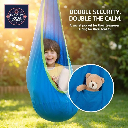 Child smiling in a blue sensory swing with security pocket holding a teddy bear outdoors.