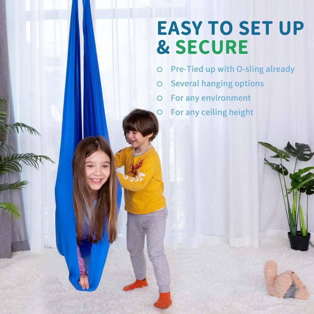 Two children playing with a blue sensory swing in a bright, cozy living room