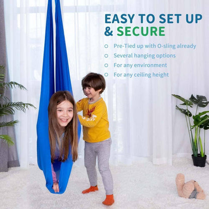Two children playing with a blue sensory swing in a bright, cozy living room