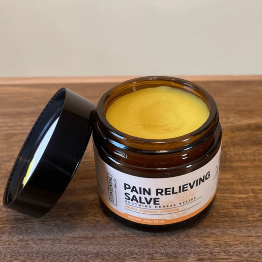 Open jar of  salve with herbal ingredients on wood surface