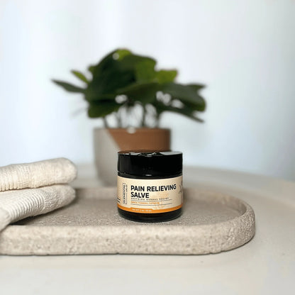 Pain relieving salve jar on tray with towels, herbal remedy for natural pain relief