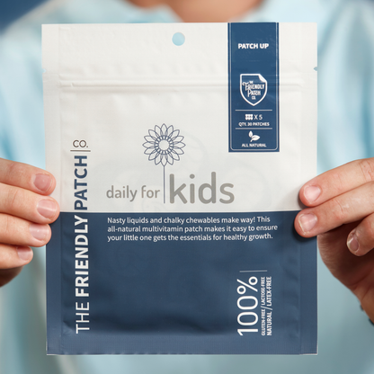 Package of 'The Friendly Patch' daily multivitamin for kids held by hands against a light blue background.