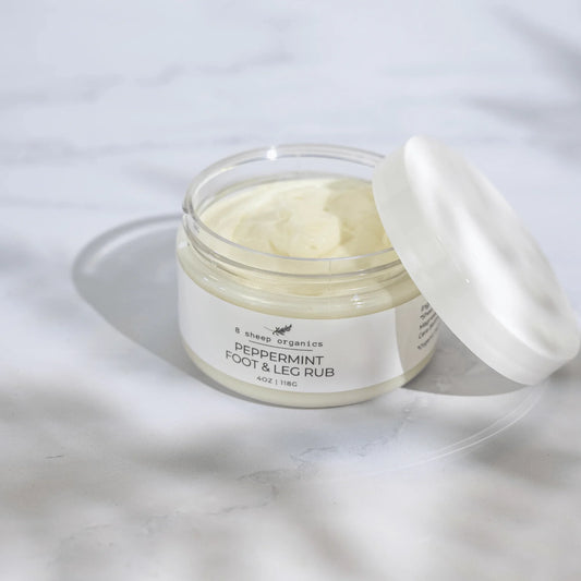 A close-up view of a cooling peppermint body cream jar sitting on a light marble surface.
