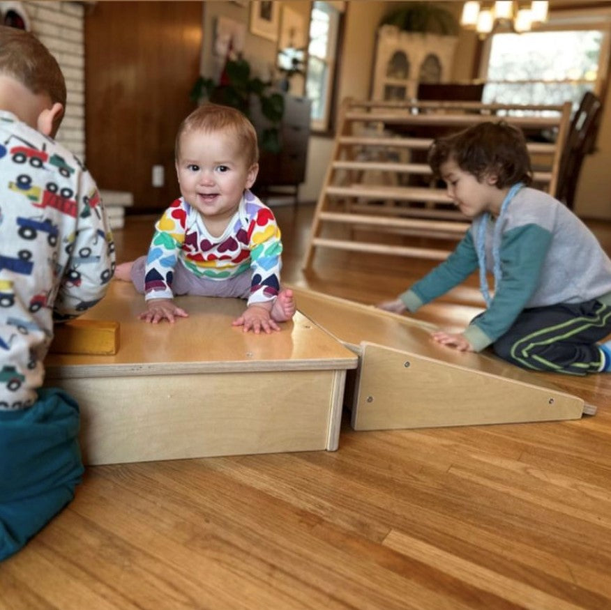 Three children playing with wooden toys on a wooden floor.