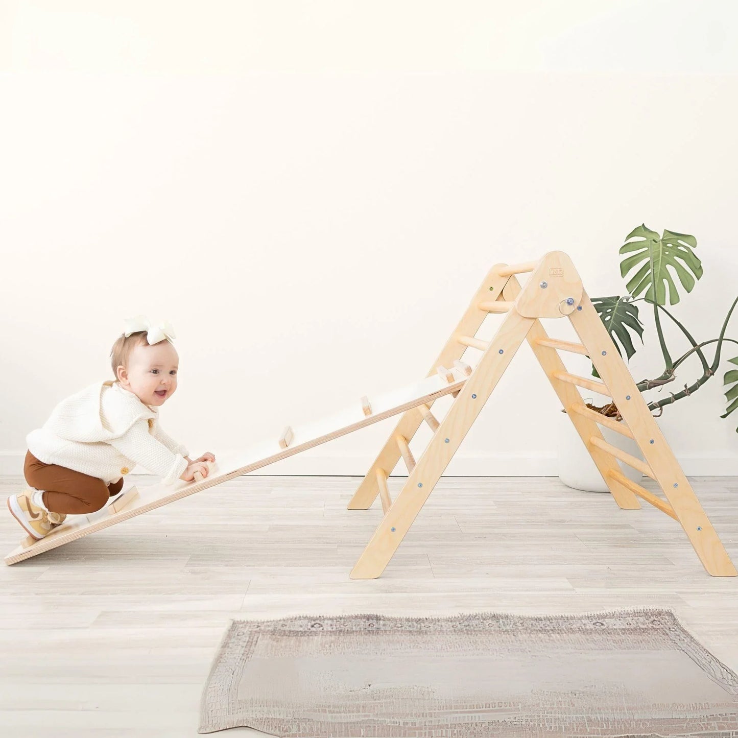 Baby climbing wooden Pikler triangle play set with ramp in a bright room
