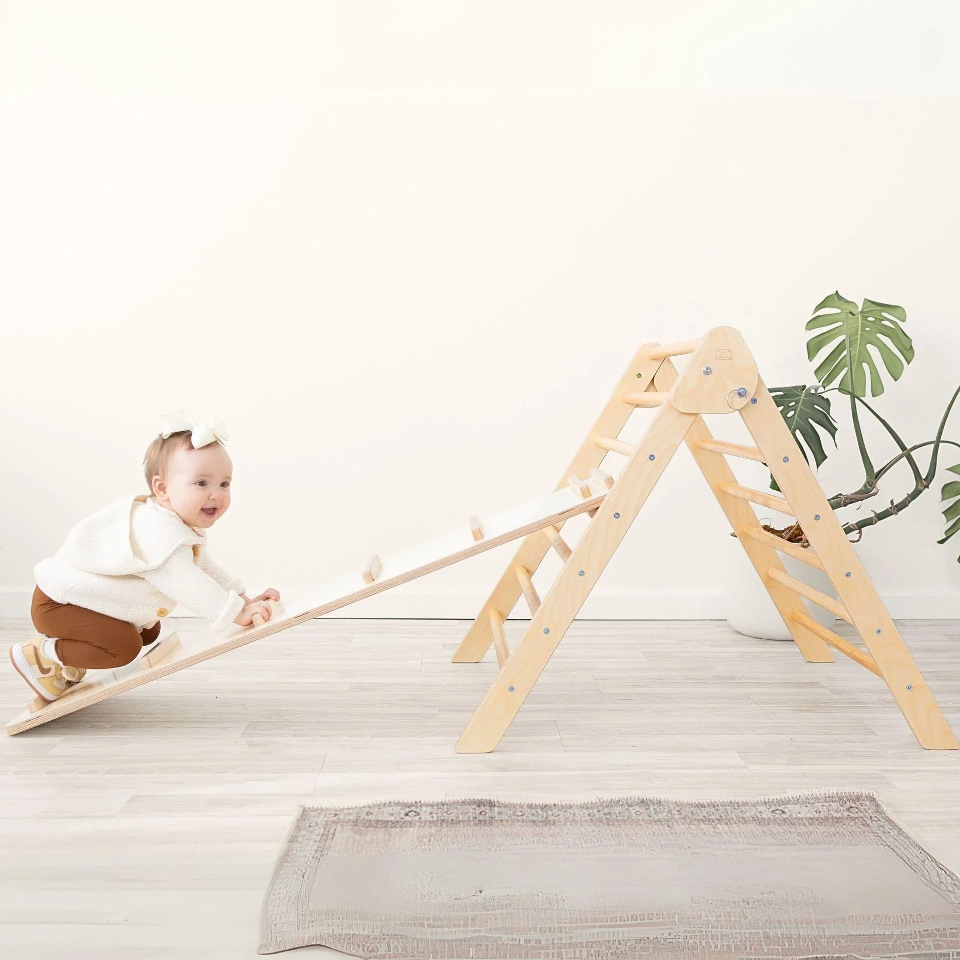 Baby climbing wooden Pikler triangle play set with ramp in a bright room