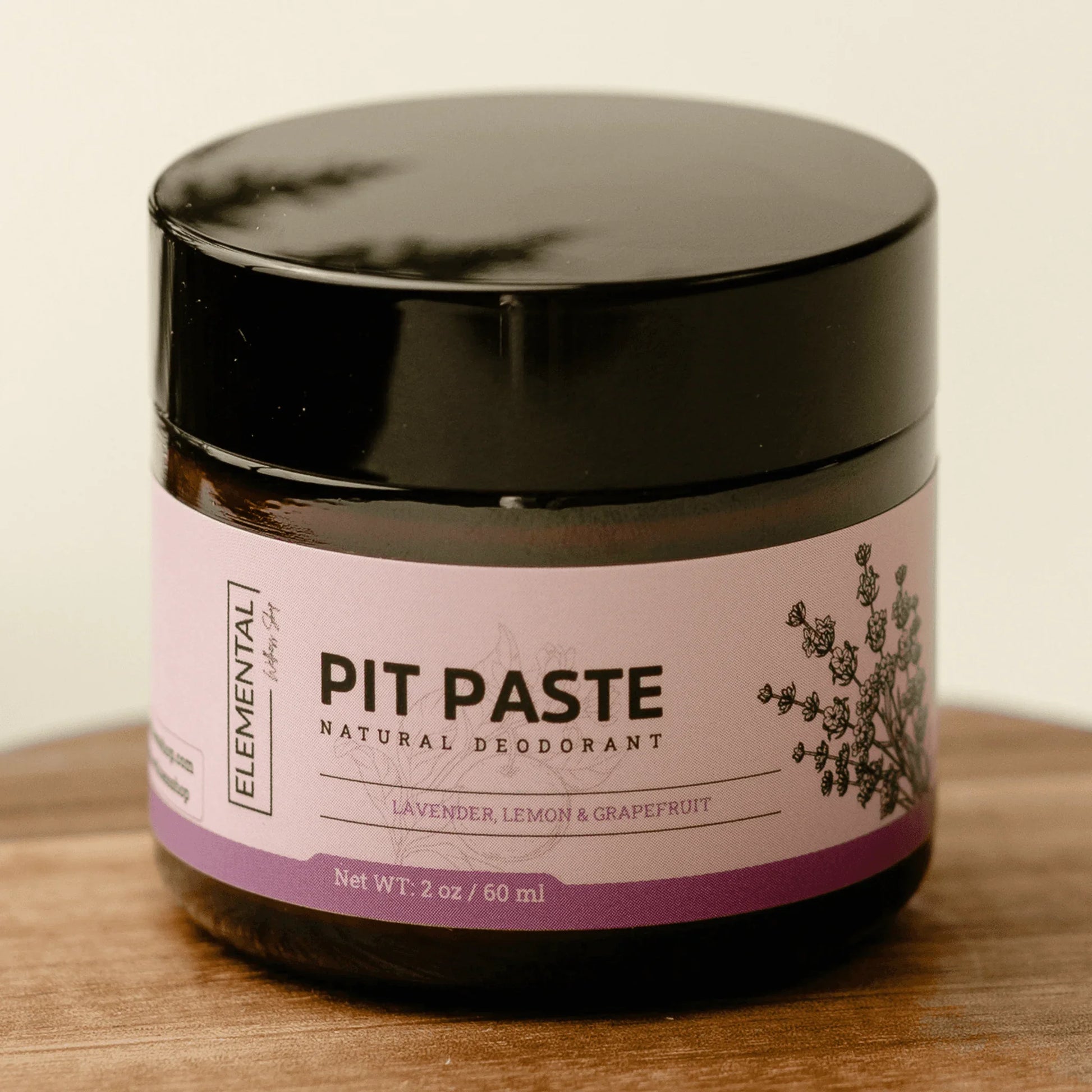 Natural deodorant jar labeled Pit Paste with lavender, lemon, and grapefruit on wooden surface