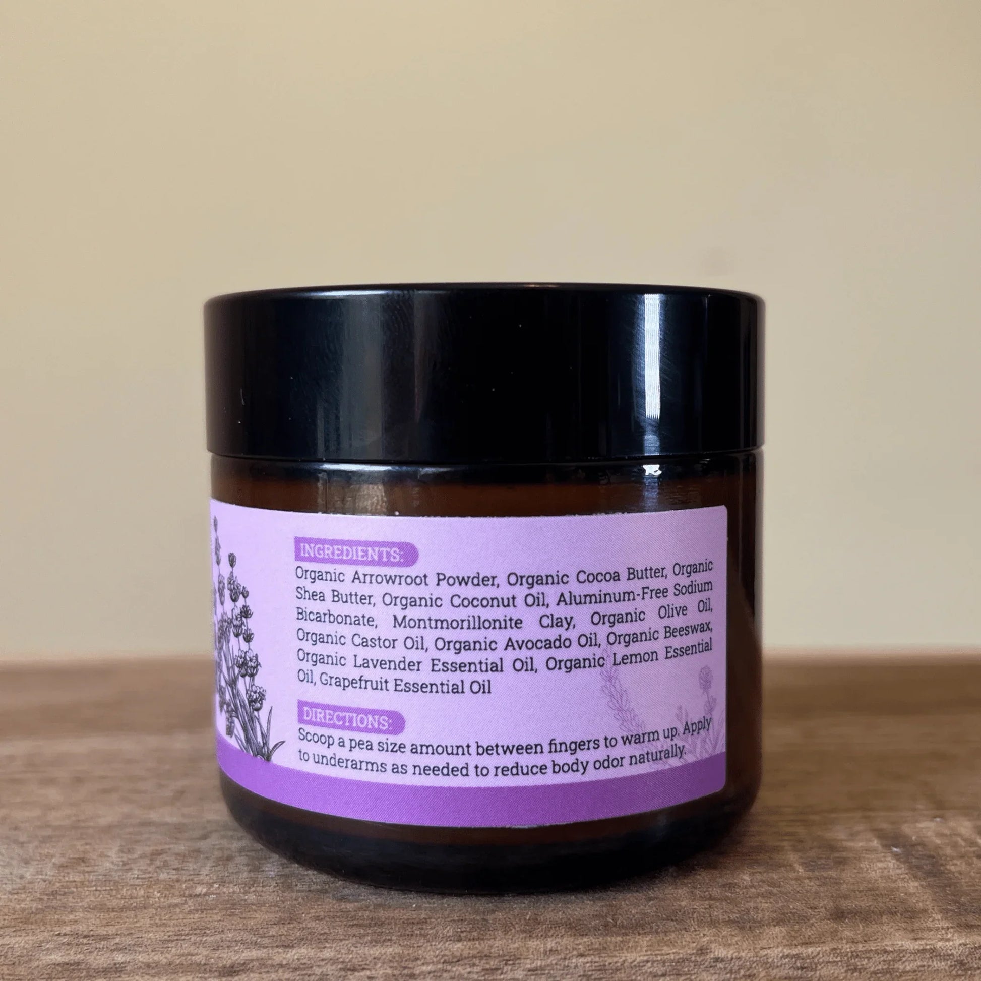 Natural deodorant jar with ingredients label and purple text on wood surface