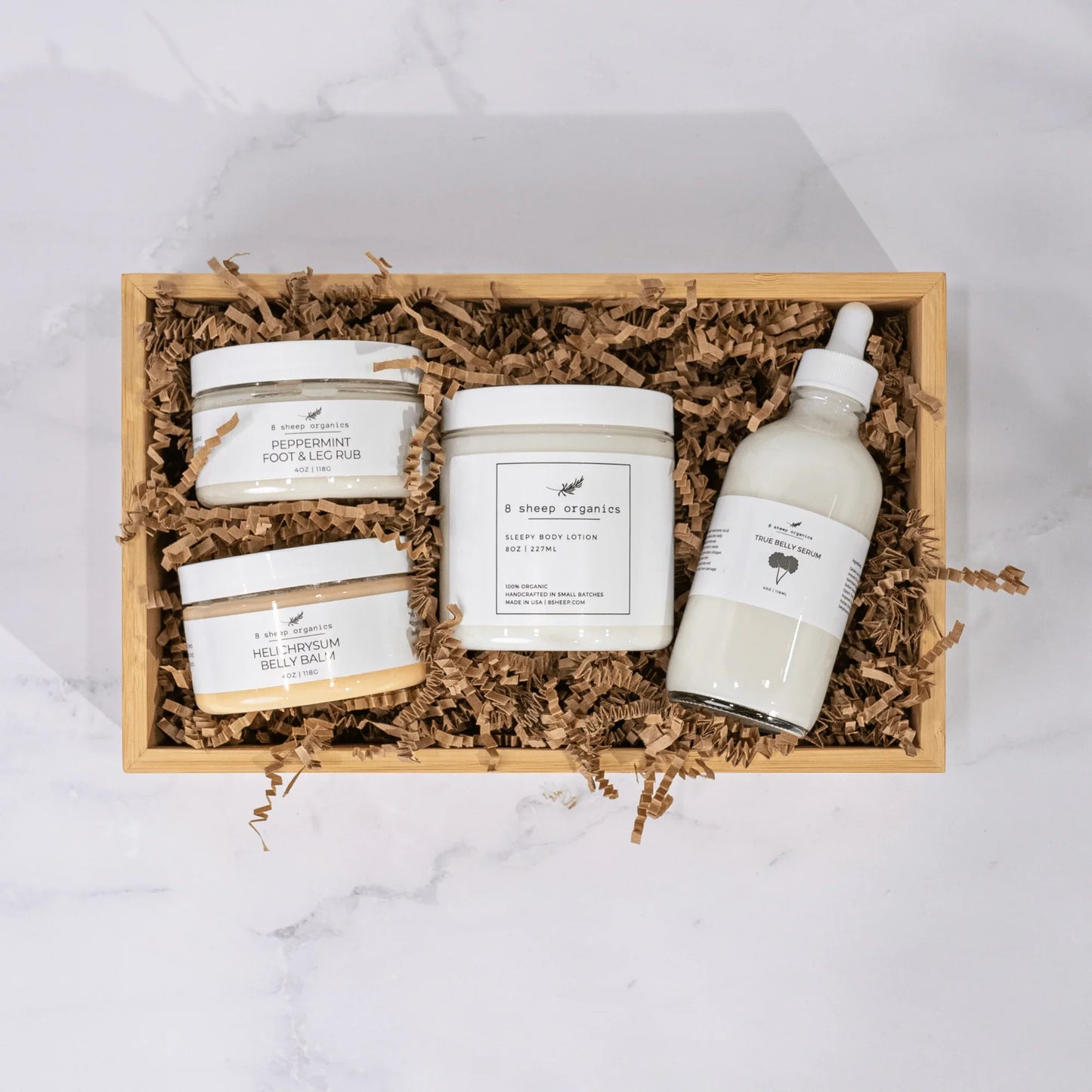 Gift box with 8 Sheep Organics lotions, foot and leg rubs, and belly serum on shredded paper.