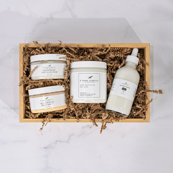 Gift box with 8 Sheep Organics lotions, foot and leg rubs, and belly serum on shredded paper.