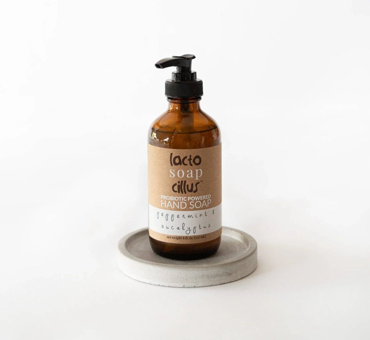 Amber pump bottle of gentle liquid hand soap for sensitive skin displayed on a clean round tray.