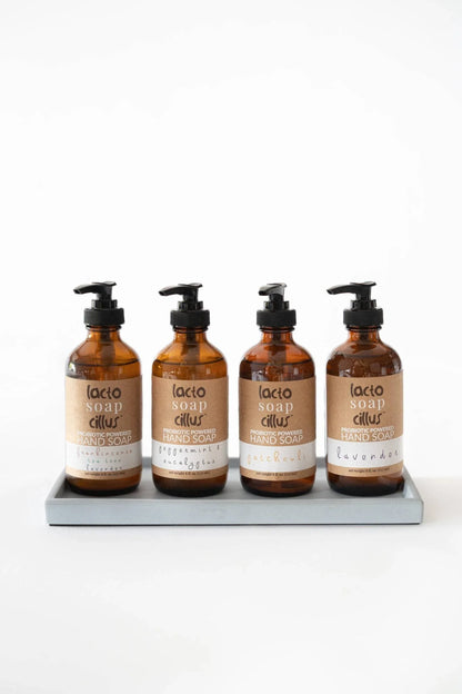 Four amber bottles of probiotic hand soap on a tray, labeled with different scents.
