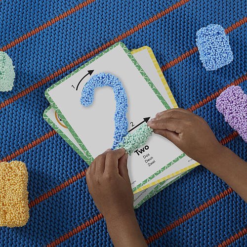 Child's hands interacting with a educational puzzle on a colorful textured surface