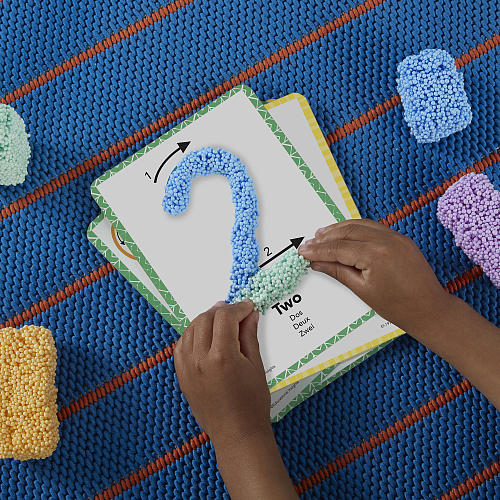 Child's hands interacting with a educational puzzle on a colorful textured surface
