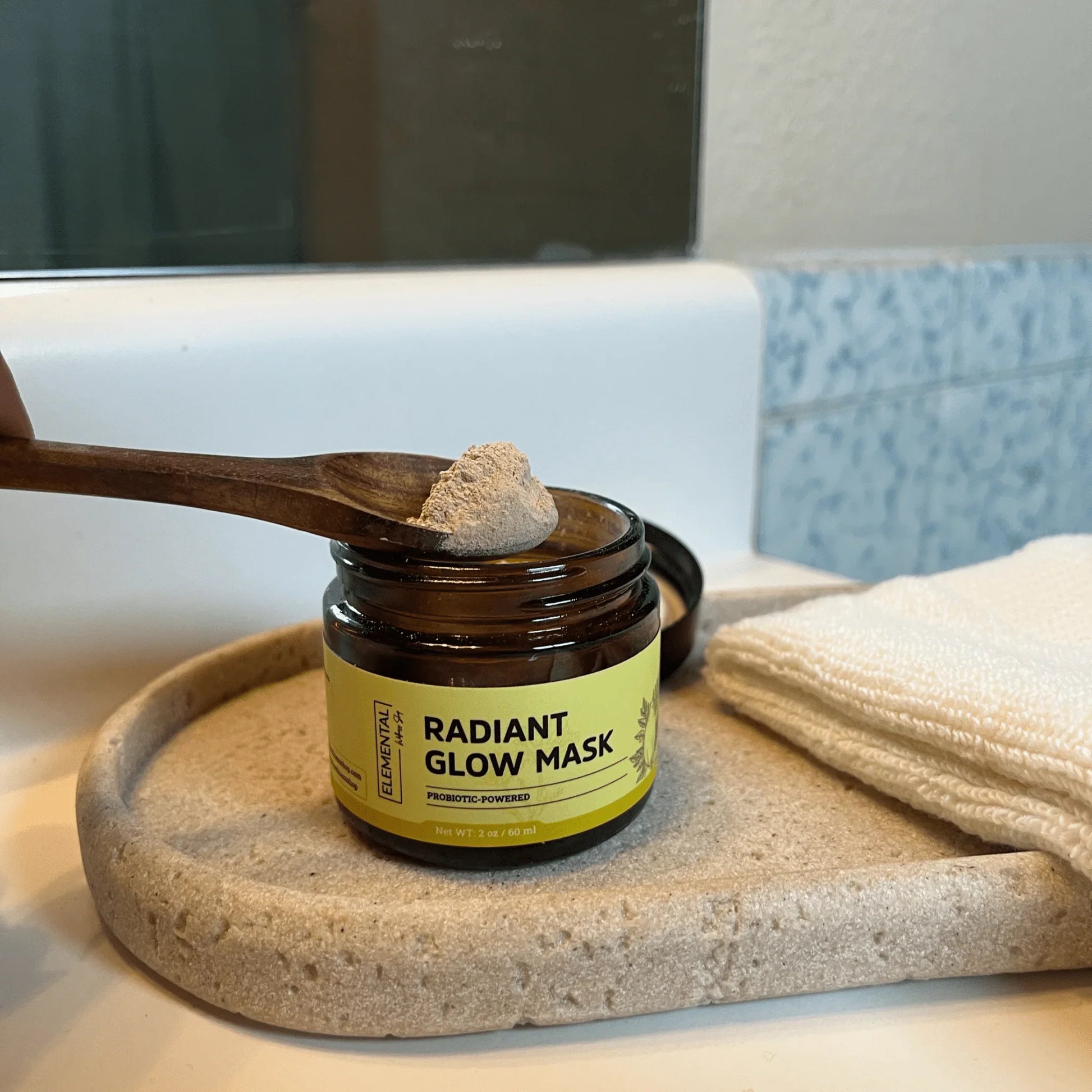 Radiant Glow Mask face mask powder in amber jar with wooden spoon on bathroom counter