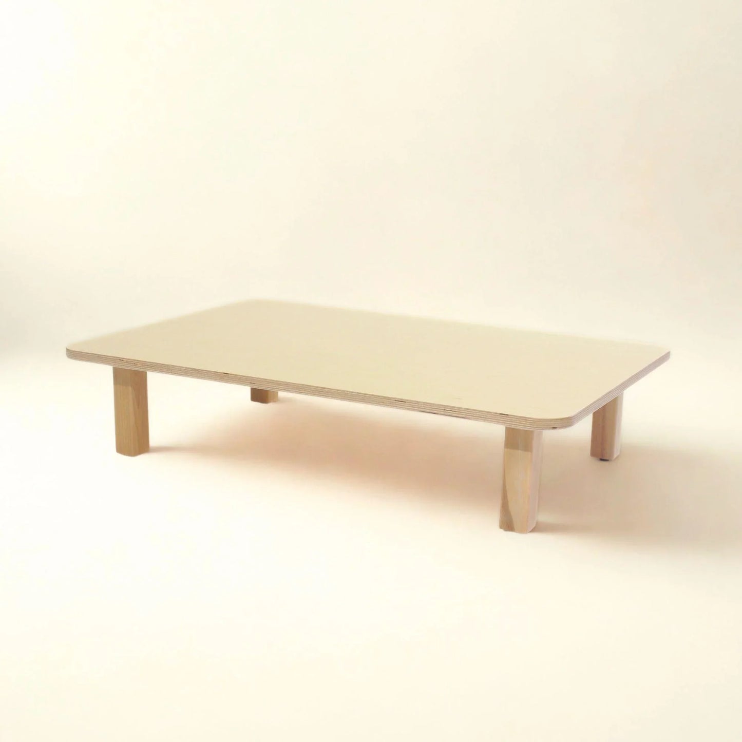 Rectangular wooden infant table with rounded corners and short legs, neutral background
