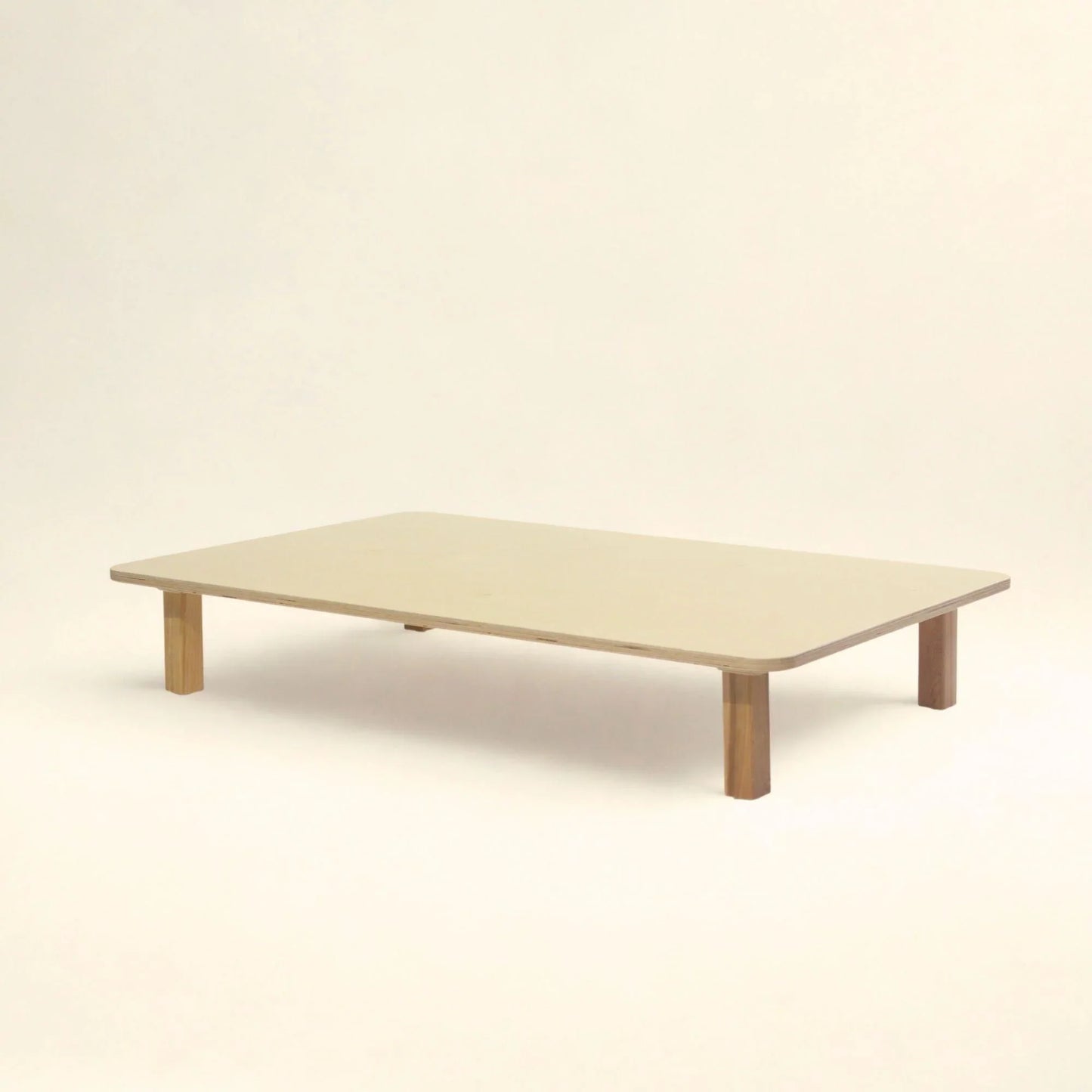 Low wooden rectangular infant table with rounded edges on a plain background