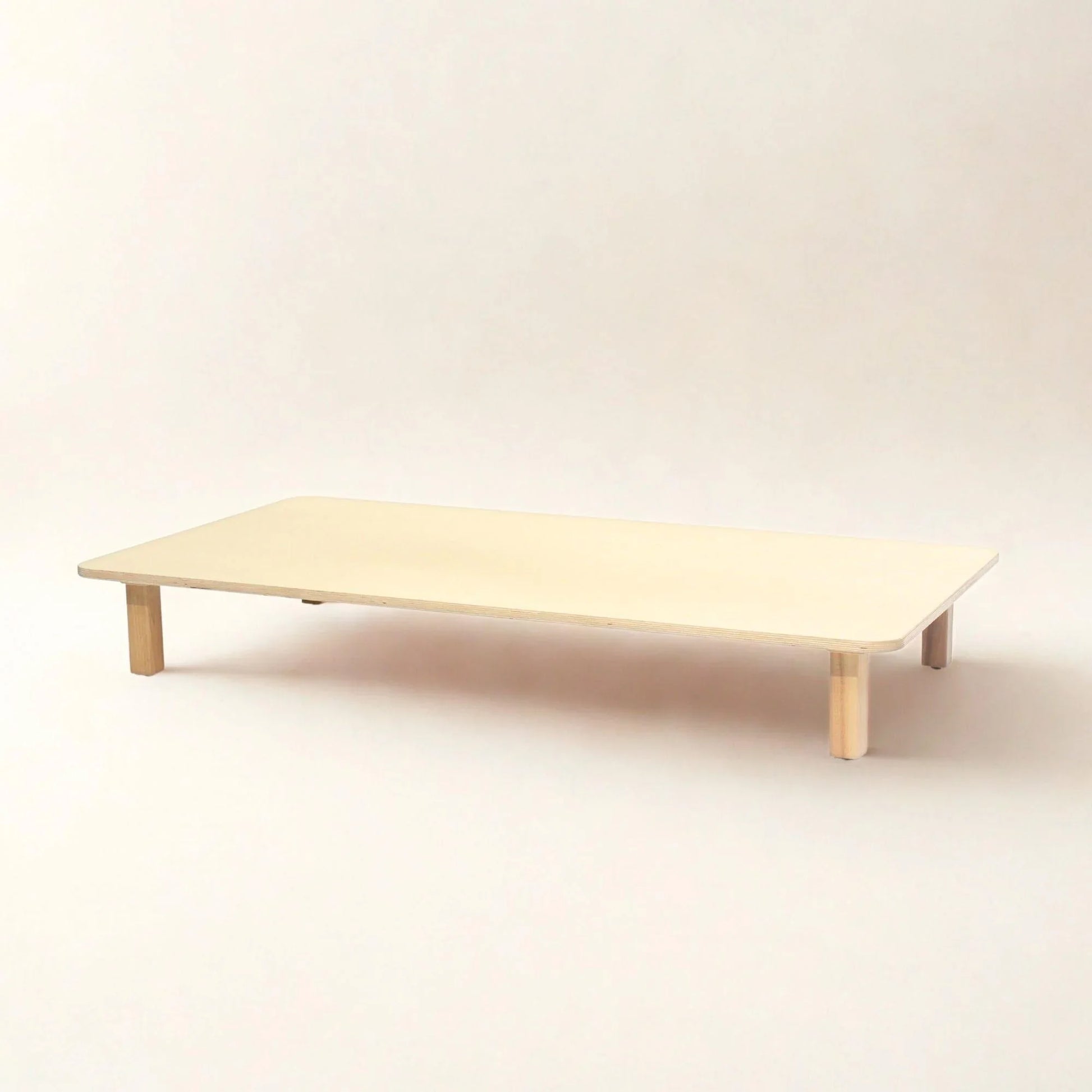 Low rectangular wooden infant activity table with rounded corners on white background