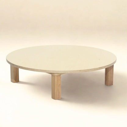 Low round wooden infant table with four sturdy legs on neutral background