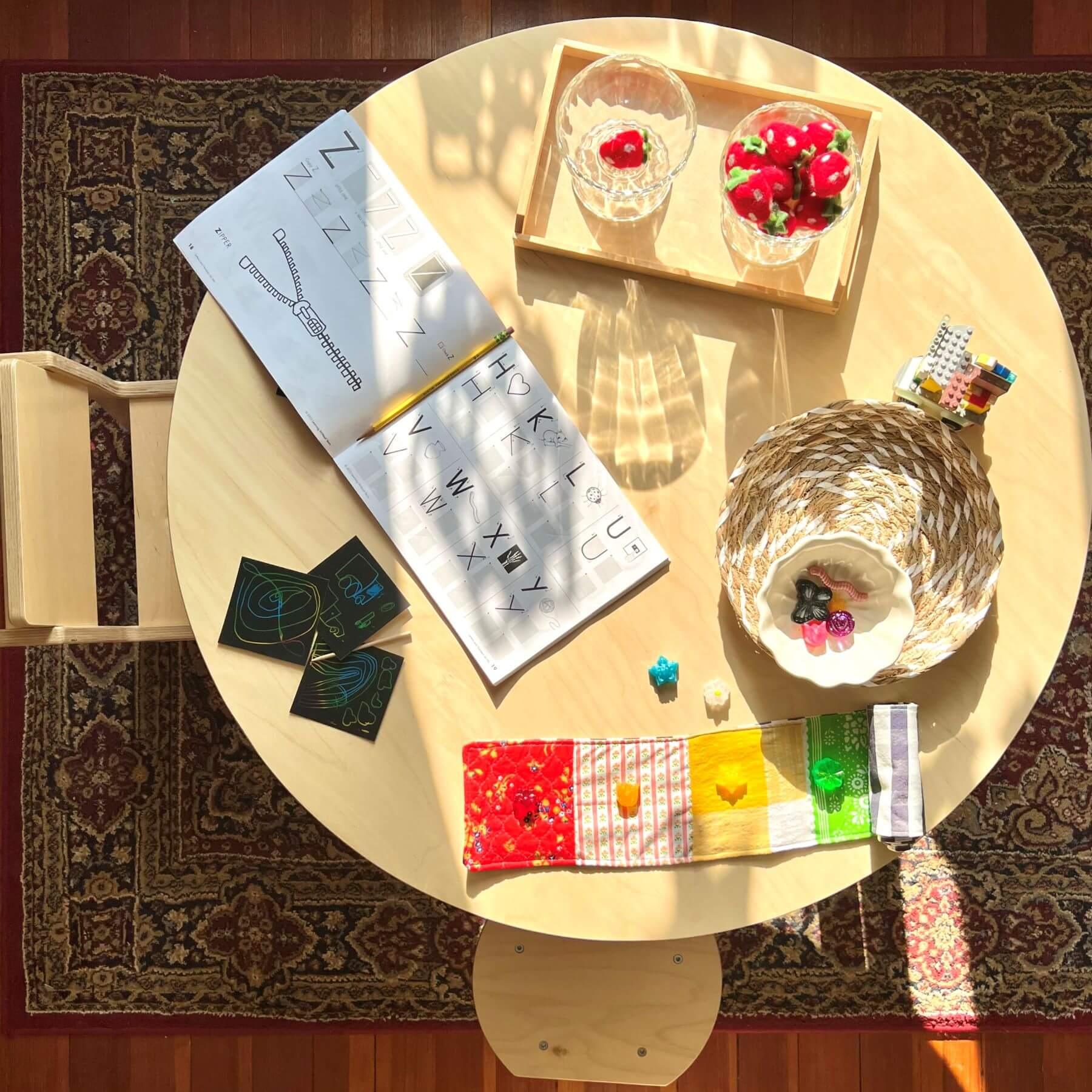 Round Montessori table with alphabet workbook, sensory toys, and educational activities
